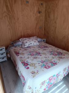 a bedroom with a bed with a floral bedspread at Cabaña en la naturaleza in Puerto Montt