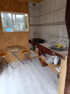 a kitchen with a sink and a counter with stools at Cabaña en la naturaleza in Puerto Montt