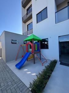 a playground with a slide in front of a building at Cantinho da Manu in Blumenau