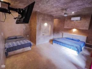 a room with two beds and a tv in it at TUUK Hotel Raíces in Valladolid