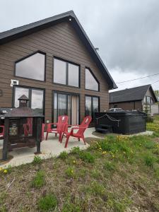 a house with two red chairs and a grill at Le Chal'Heureux in Saint Adelphe