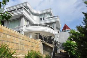 a white house with a staircase in front of it at Hotel Minahasa Manado in Manado