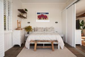a bedroom with a bed and a bench in it at Bay Properties The Beach House in Yamba