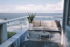 a couch sitting on a balcony with the ocean at Bay Properties The Beach House in Yamba