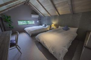 Un dormitorio con dos camas y una ventana en COCO VILLA 湯布院-Yufuin-, en Yufu