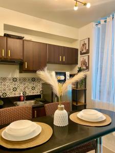 a kitchen with a table with white plates on it at Cozy Cabin by JLS Near Venice Grand Canal Mall in Manila