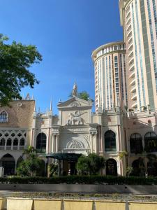 a building with a statue in front of two tall buildings at Cozy Cabin by JLS Near Venice Grand Canal Mall in Manila