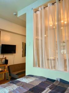 a bedroom with a window with a bed and a television at Cozy Cabin by JLS Near Venice Grand Canal Mall in Manila +7 photos