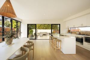 a kitchen with white cabinets and a long island with chairs at Villa Ponte, 3BR Villa, private pool in New Farm in Brisbane
