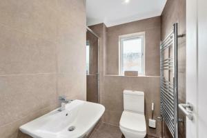 a bathroom with a white toilet and a sink at Charming 1BD Flat with Parking in Bromley in Grove Park