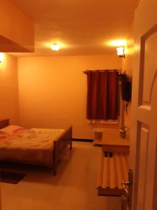 um pequeno quarto com uma cama e uma janela em Sousam Cottage em Kodaikānāl