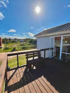 eine Holzterrasse mit einer Bank auf einem Haus in der Unterkunft Casitas Punta del Diablo in Punta Del Diablo + 68 Fotos