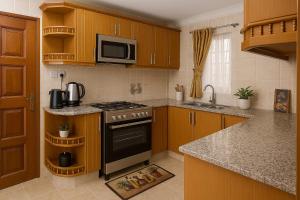 a kitchen with wooden cabinets and a stove top oven at Riverside Spacious Getaway in Nairobi