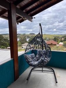 a hanging chair on a balcony with a view at Estadia Barragem do Salto - Casa Mugam in São Francisco de Paula