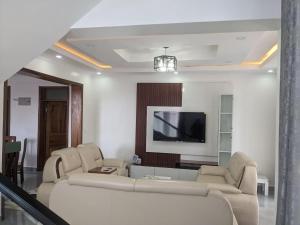 a living room with couches and a flat screen tv at Luxury Mansion for Rent in Kigali
