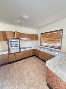a large kitchen with wooden cabinets and a window at Spacious Queen Room in Comfortable Two Story House - L2 