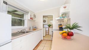 a kitchen with white cabinets and a bowl of fruit on the counter at Flipside Apartment in Kiama