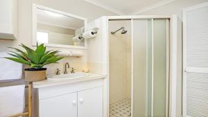 a white bathroom with a sink and a shower at Flipside Apartment in Kiama