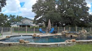 a pool in a yard with two chairs and an umbrella at Bluebird Hill and Star Suite home in Rio Frio