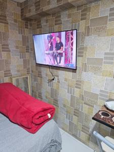 a flat screen tv hanging on a brick wall at Espaço para duas pessoas, 5 minutos do centro de Sao Bernardo do Campo in São Bernardo do Campo