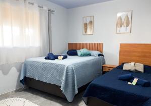 a bedroom with two beds with blue sheets and a window at Inn Nature Pousada Casa de Veraneio com piscina in Palhoça +25 photos