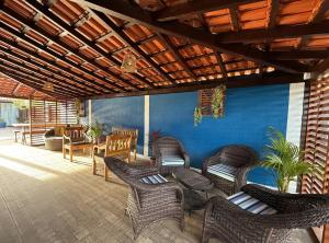 a patio with wicker chairs and a blue wall at Inn Nature Pousada Casa de Veraneio com piscina in Palhoça