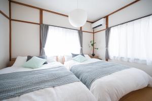 Dos camas en una habitación con ventana. en Happiness Ohama一軒家東名静岡インター五分, en Shizuoka