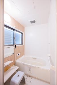 Un baño blanco con bañera y lavabo. en Happiness Ohama一軒家東名静岡インター五分, en Shizuoka 14 fotos más