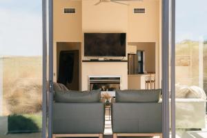 a living room with sliding glass doors and a tv at Cardrona Alpine Villa by Sothebys Luxury Rental Homes in Cardrona