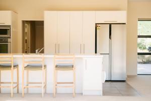 a kitchen with white cabinets and a counter with stools at Cardrona Alpine Villa by Sothebys Luxury Rental Homes in Cardrona