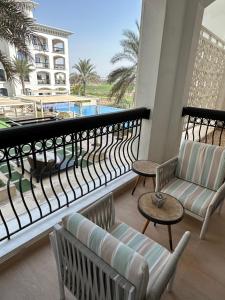 d'un balcon avec des chaises et des tables offrant une vue sur la piscine. dans l'établissement F1 - Ivy Studio Golf View Ansam Yas Island, Theme Parks, à Abu Dhabi