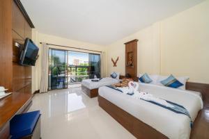 a hotel room with two beds and a television at JR Siam Inn Resort in Kata Beach