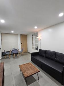 een woonkamer met een zwarte bank en een tafel bij NSI Alameda Park Humboldt Mexico City in Mexico-Stad