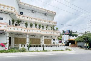 Un gran edificio blanco con un balcón a la calle. en RedDoorz near Simpang Panei Medan, en Pematangsiantar