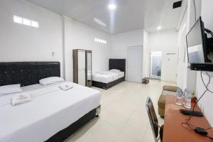Un dormitorio con dos camas y un escritorio y un televisor. en RedDoorz near Simpang Panei Medan, en Pematangsiantar