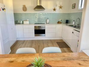 a kitchen with white cabinets and a table and chairs at Osprey - Pet Friendly Waterfront in Callala Bay
