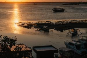 a group of boats in the water at sunset at Nipper Resort & Villa Nusa Dua in Ujung