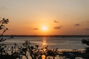 a sunset over a body of water at Nipper Resort & Villa Nusa Dua in Ujung