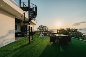 a house with a balcony with a table and a spiral staircase at Nipper Resort & Villa Nusa Dua in Ujung