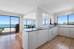 a kitchen with white cabinets and a view of the ocean at IL Mare - "Expansive Ocean Views" in Apollo Bay