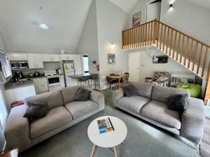 a living room with two couches and a kitchen at 15b Caverhill Close in Hanmer Springs