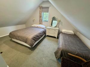 a attic bedroom with two beds and a mirror at 15b Caverhill Close in Hanmer Springs