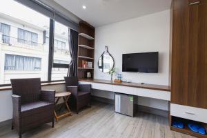 a room with a desk with a tv and chairs at HAKU Boutique Hotel Tuy Hoà - APEC Mandala in Tuy Hoa