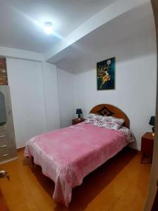 a bedroom with a bed with a pink blanket at OASIS Cusco in Cusco