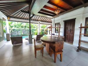a dining room with a wooden table and chairs at Cozy two bed room with swiming pool in Ubud