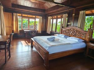 a bedroom with a bed and a table and windows at Cozy two bed room with swiming pool in Ubud