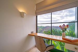 a room with a desk and a window with a vase of flowers at Villa Ceylon 4 Uluwatu in Uluwatu