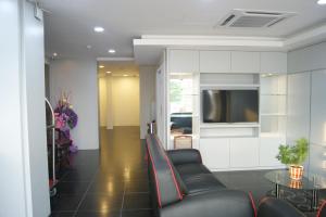 a living room with black leather chairs and a tv at Double Happiness Hotel in Seri Manjung