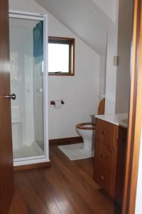 uma casa de banho com um WC e uma cabina de duche em vidro. em Tui Hideaway em Invercargill