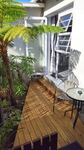 a balcony with a wooden floor and a table and a tree at The Little Homestead in Gqeberha